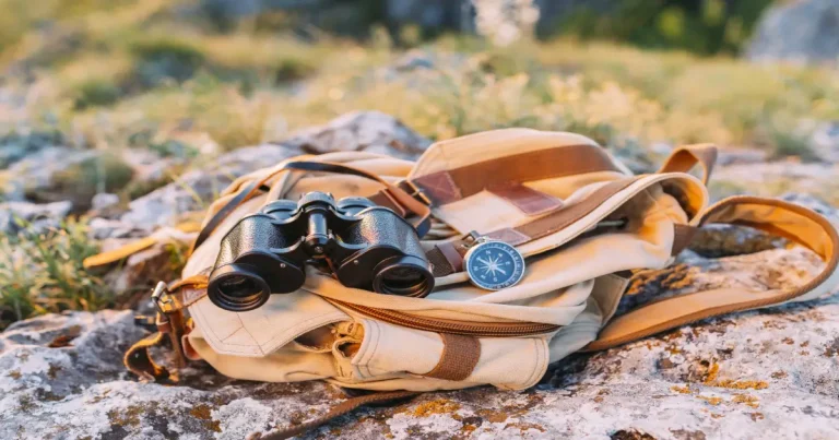 Kenya safari packing essentials laid flat: khaki shirt, binoculars, sun hat, insect repellent